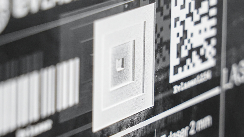 Dettaglio macro di marcatura laser UV su plexiglass trasparente opacizzazione bianca ad alta precisione con micro-incisione e codice DataMatrix