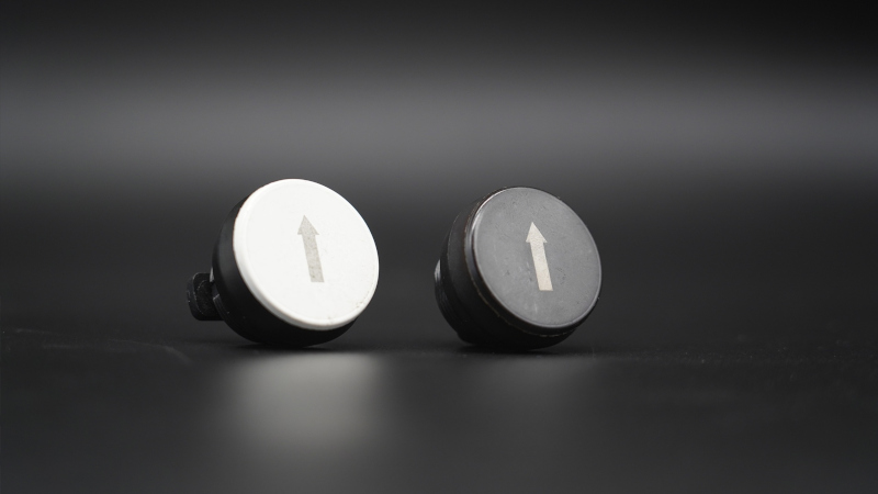 Comparison of laser marking on white and black plastic buttons with high-precision engraved symbol