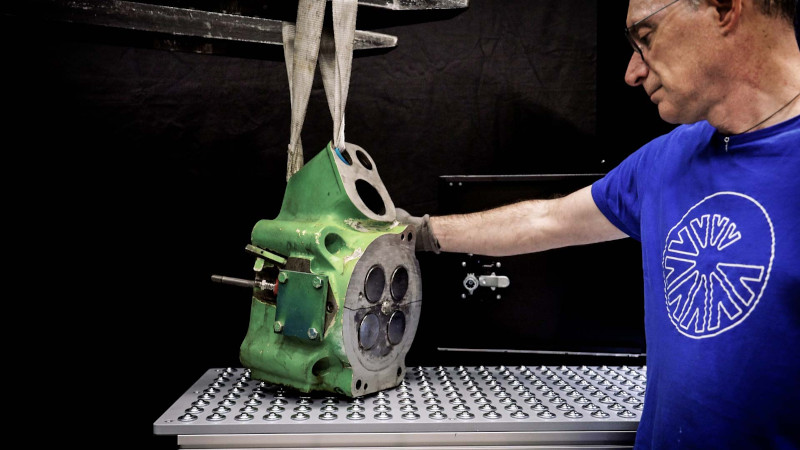 Operator positioning a heavy metal component for laser marking on an industrial workstation