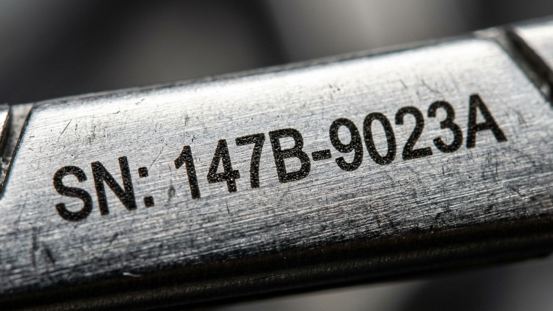 Laser annealing marking of a serial number on a steel component for industrial traceability.